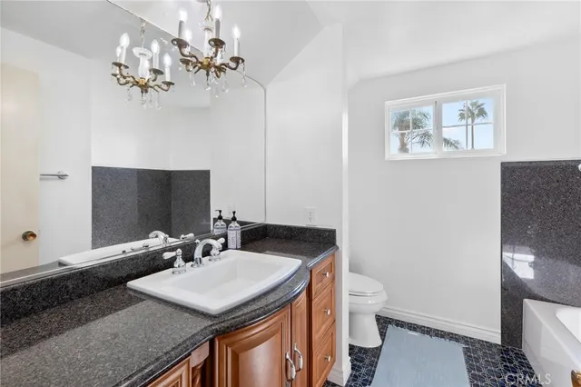 a bathroom with a granite countertop sink a toilet and a mirror