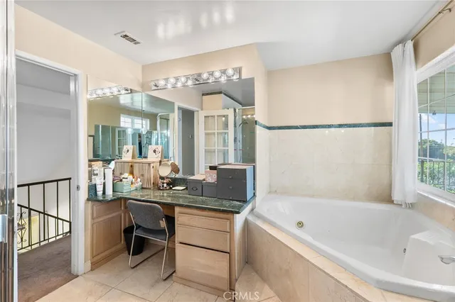 a bathroom with a granite countertop bathtub a sink and a large mirror