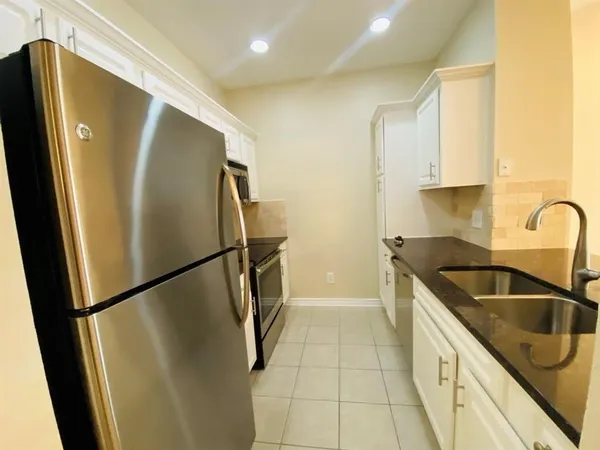 a kitchen with stainless steel appliances a refrigerator a sink a stove and white cabinets
