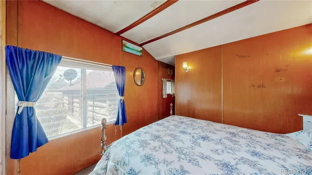 a bedroom with wooden floor and windows
