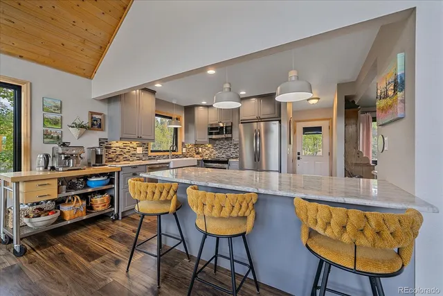 a large living room with stainless steel appliances kitchen island granite countertop a table chairs and a couch