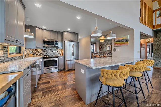 a kitchen with stainless steel appliances kitchen island granite countertop a table chairs and a refrigerator