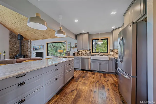 a large kitchen with stainless steel appliances a large counter top a sink a window and wooden floor