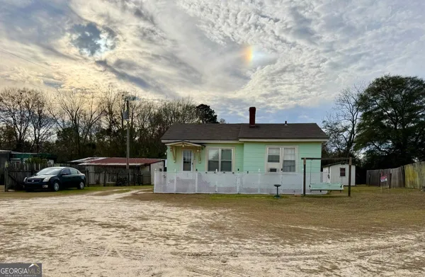 a view of a white house with a big yard and large trees