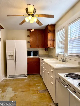 a kitchen with stainless steel appliances granite countertop a sink a stove a refrigerator cabinets and a dining table
