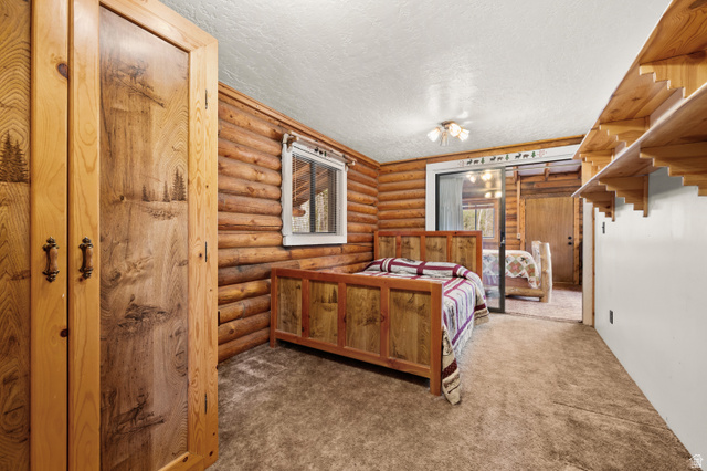 4725 Pine Ridge Road Evanston, UT 82930 - Photo 29 of 82 Wood-clad interior featuring log walls, decorative wood-carved armoire, a ceiling-mounted light fixture, and built-in shelving