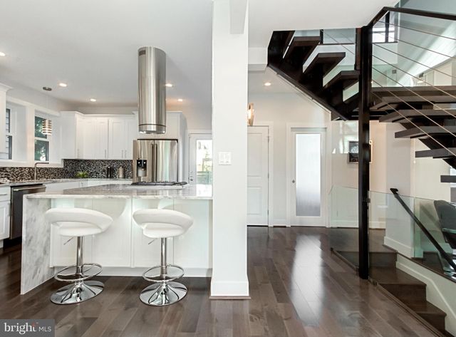 a kitchen with stainless steel appliances granite countertop a refrigerator a stove and white cabinets with wooden floor