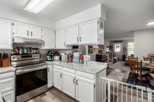 a kitchen with kitchen island granite countertop a sink a stove and cabinets
