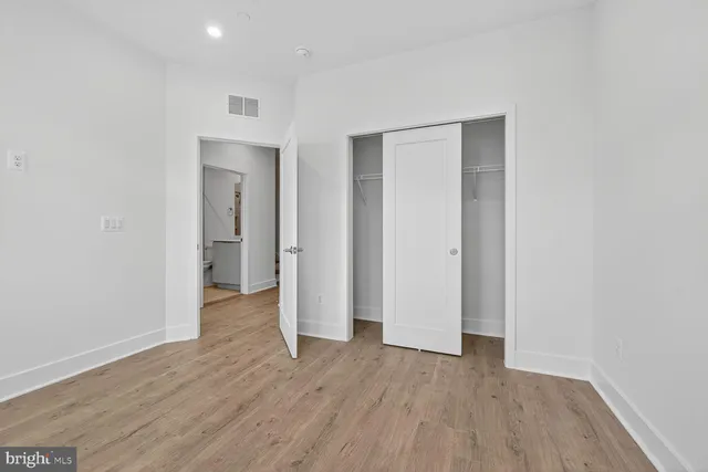 a view of an empty room with wooden floor and windows