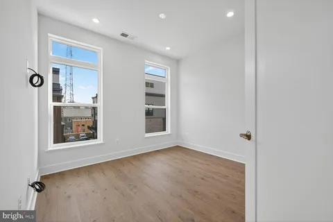 a view of an empty room with wooden floor and closet