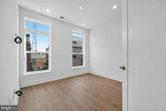 a view of an empty room with wooden floor and closet