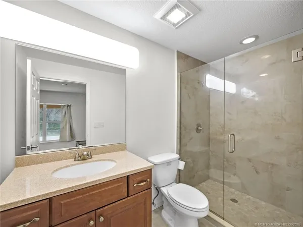 a bathroom with a sink a toilet a mirror and shower