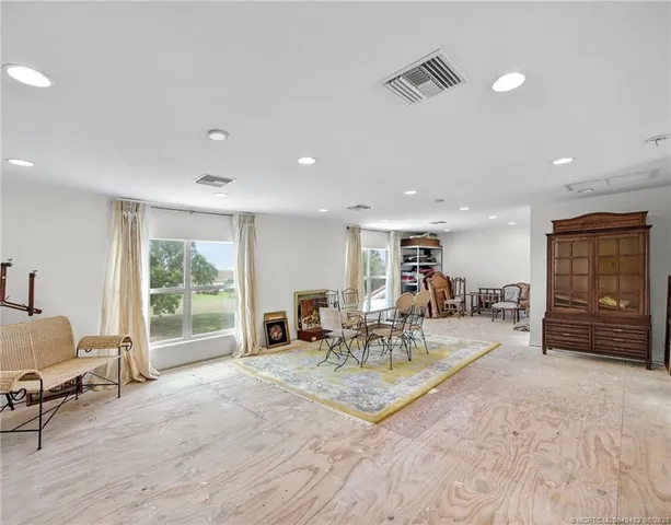 a living room with furniture a flat screen tv and floor to ceiling window