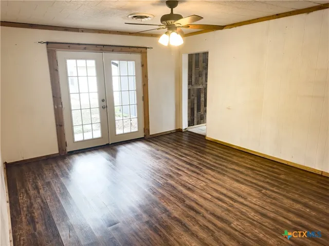 a view of an empty room with wooden floor and a window