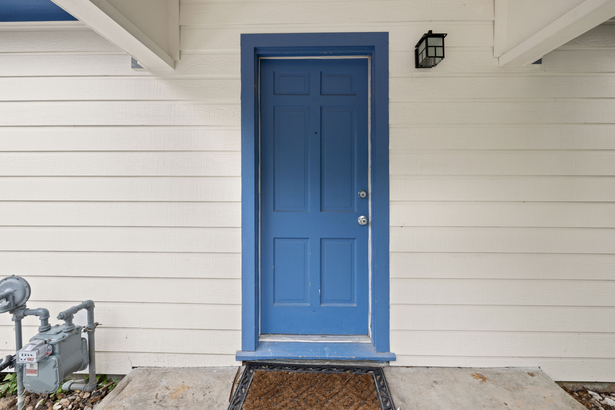907 East 53rd Street Austin, TX 78751 - Photo 4 of 36 A striking blue entry door creates a vibrant focal point on the clean, white-sided facade.