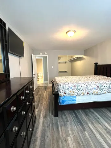 a bedroom with a large bed and a flat tv screen on dresser