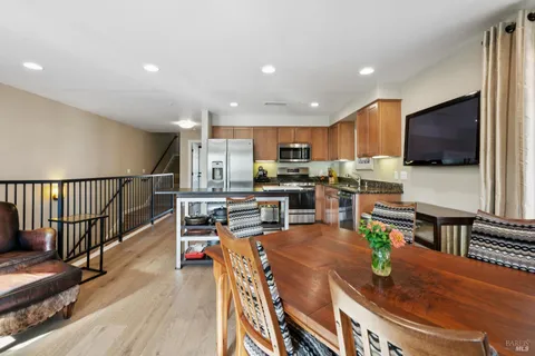 a kitchen with stainless steel appliances wooden floor dining table and chairs