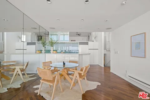 a dining room with stainless steel appliances kitchen island granite countertop a dining table chairs and a refrigerator