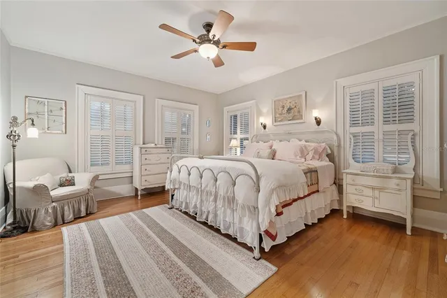 a bedroom with a large bed a chandelier and windows