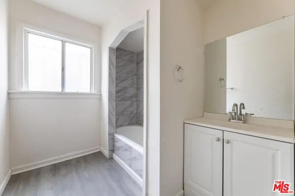 a bathroom with a granite countertop sink a mirror and a bathtub