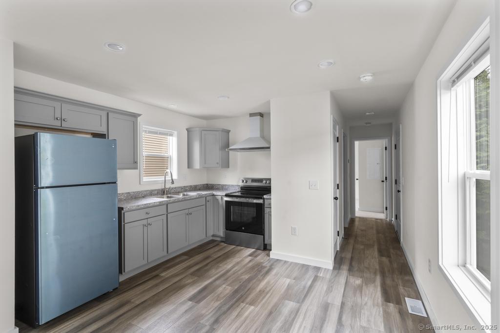 55 Sugar Street, Unit 2 Newtown, CT 06470 - Photo 3 of 19 a kitchen with a refrigerator a stove top oven and wooden floor