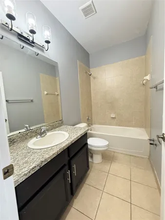 a bathroom with a granite countertop sink toilet mirror and bathtub