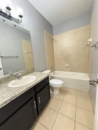 a bathroom with a granite countertop sink a toilet mirror and bathtub