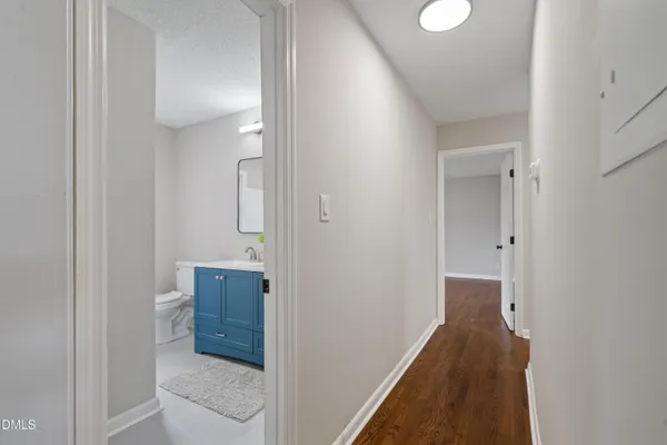 a view of a hallway with wooden floor and a bathroom