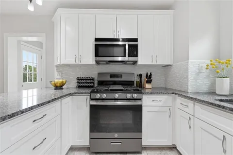 a kitchen with stainless steel appliances granite countertop white cabinets and a stove