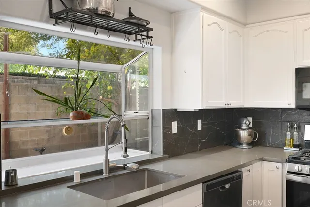 a kitchen with stainless steel appliances granite countertop a sink a stove and a wooden floor