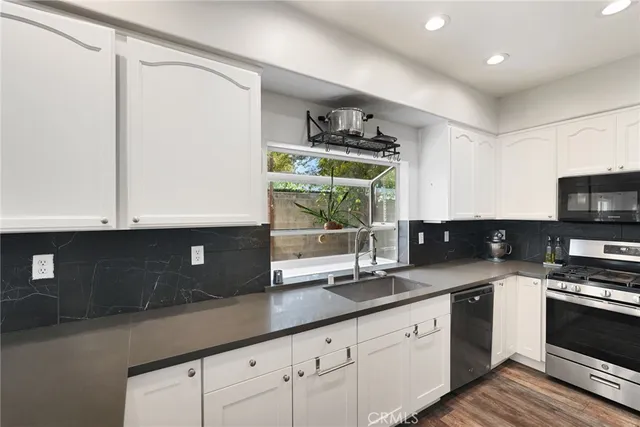 a kitchen with stainless steel appliances granite countertop a sink a stove and a microwave