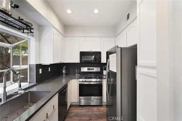 a kitchen with stainless steel appliances a refrigerator a sink and white cabinets