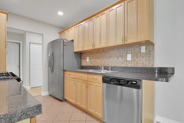 a kitchen with stainless steel appliances granite countertop a refrigerator a sink and white cabinets