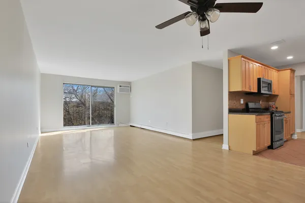 a view of kitchen and empty room with wooden floor