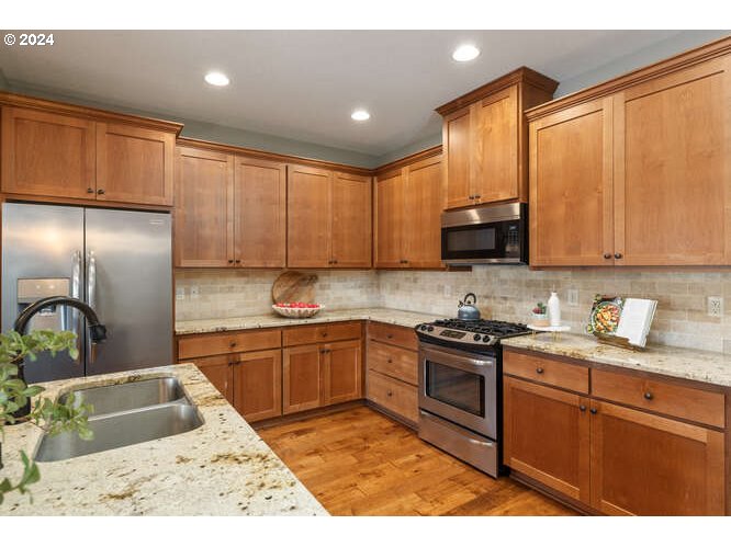 4307 Northwest Sage Loop Camas, WA 98607 - Photo 18 of 40 a kitchen with stainless steel appliances granite countertop a sink stove and refrigerator