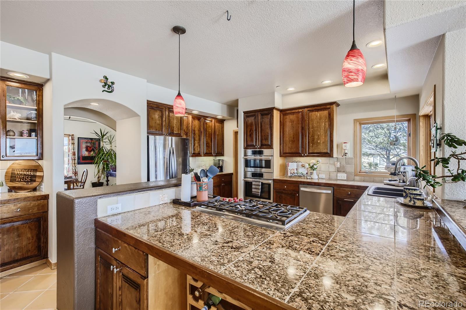 7578 Crestview Drive Niwot, CO 80504 - Photo 6 of 40 a kitchen with kitchen island granite countertop a stove a sink a refrigerator dining table and chairs