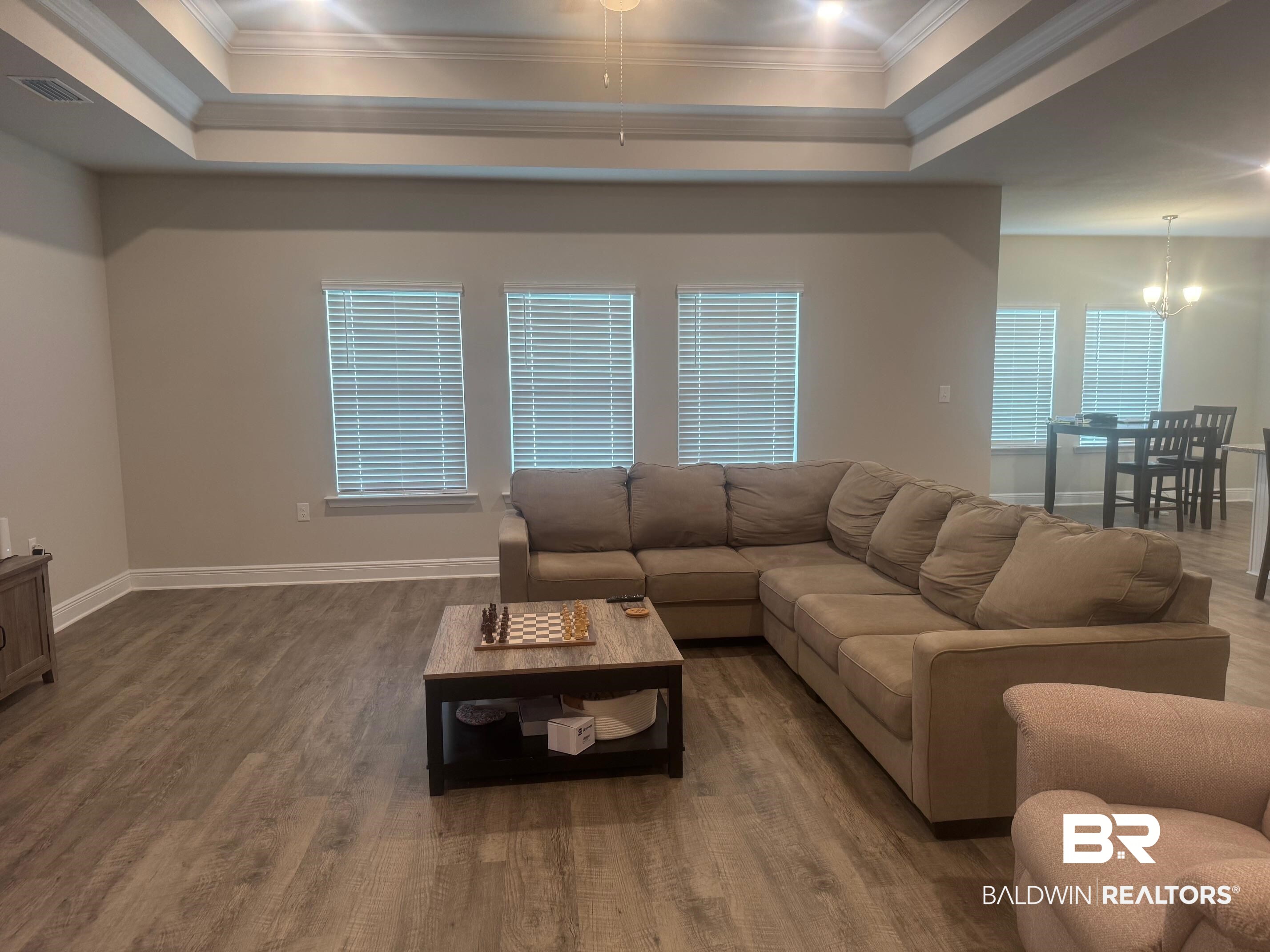 24903 Spectacular Bid Loop Daphne, AL 36526 - Photo 3 of 37 Living area with crown molding, wood finished floors, and a raised ceiling