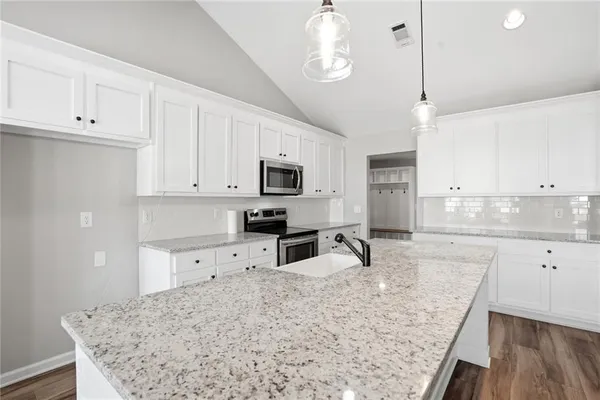 a kitchen with granite countertop a sink a counter space appliances and cabinets