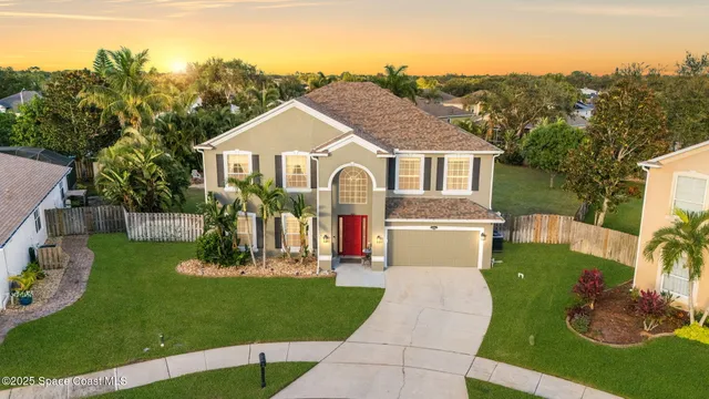 a front view of a house with garden and trees