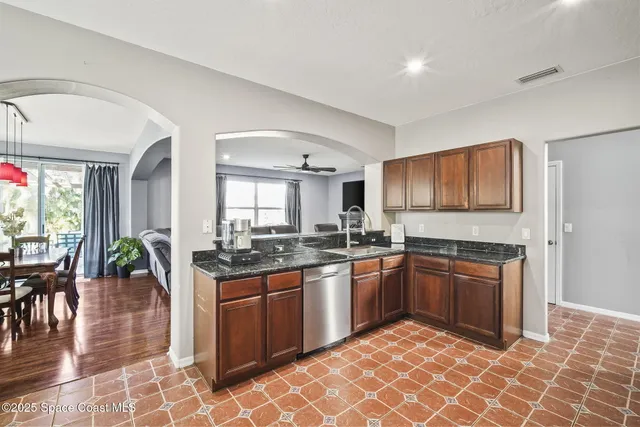 a kitchen with stainless steel appliances granite countertop a sink dishwasher a stove and a refrigerator with wooden floor