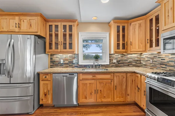 a view of a kitchen with a stove wooden cabinets and wooden floor
