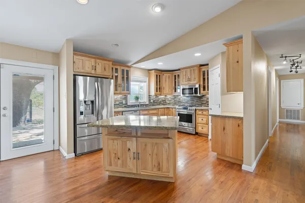 a kitchen with stainless steel appliances granite countertop a refrigerator and a stove top oven