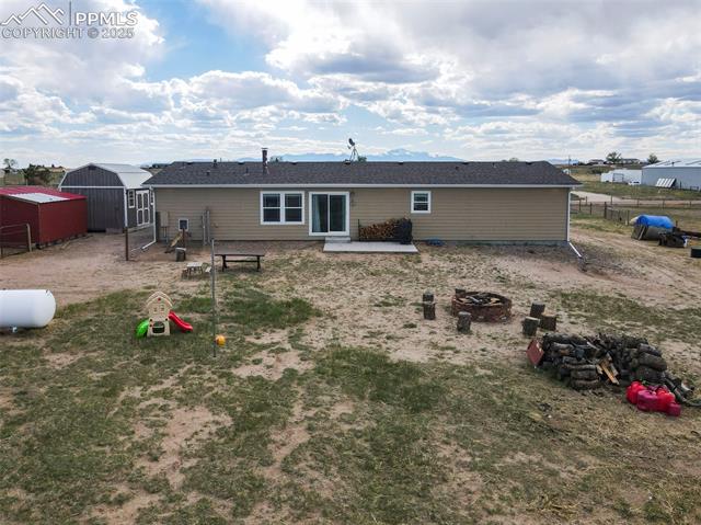 961 Buffalo Run Road Calhan, CO 80808 - Photo 15 of 45 Back of house featuring a storage unit, a patio area, and an outdoor fire pit