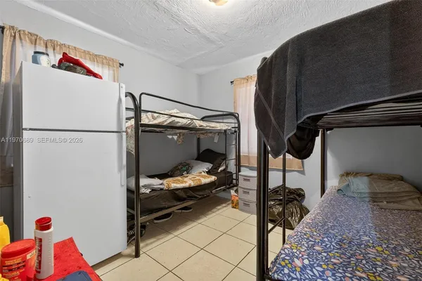 a bedroom with a bed and a refrigerator