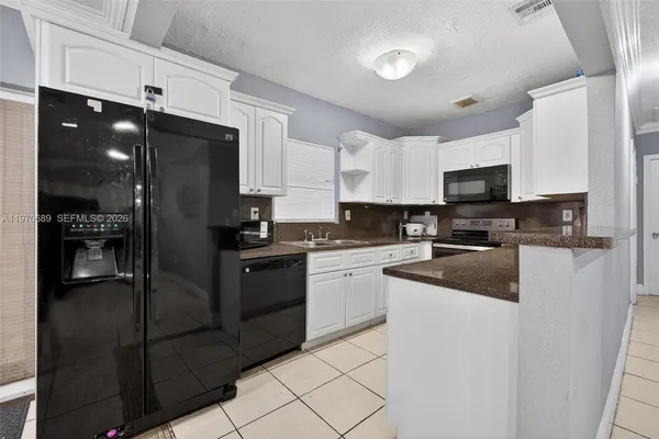 a kitchen with stainless steel appliances granite countertop a refrigerator a stove a sink and a microwave