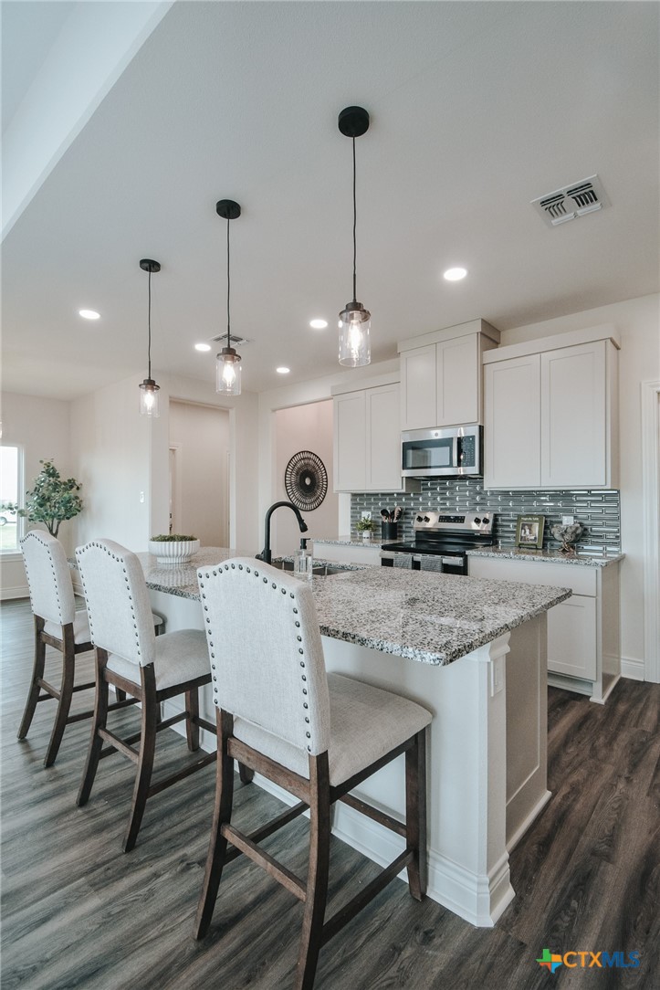 321 Whitetail Lane Victoria, TX 77905 - Photo 11 of 47 a kitchen with stainless steel appliances kitchen island granite countertop a dining table chairs and sink