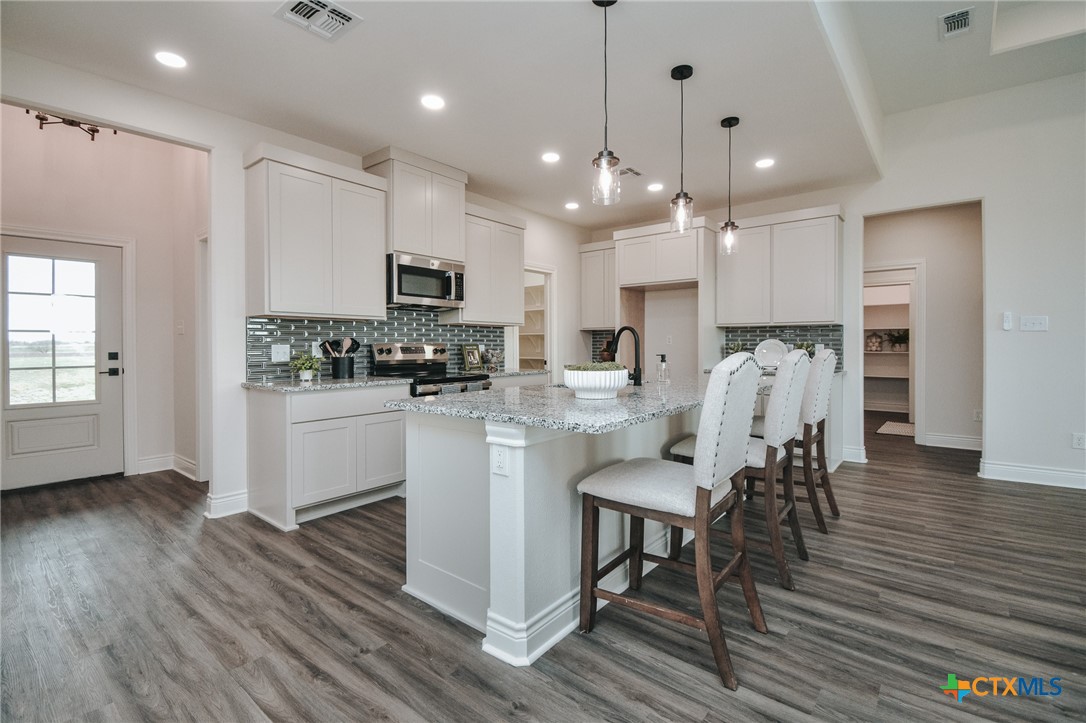 321 Whitetail Lane Victoria, TX 77905 - Photo 4 of 47 a kitchen with stainless steel appliances granite countertop a refrigerator a stove top oven a sink dishwasher and white cabinets with wooden floor