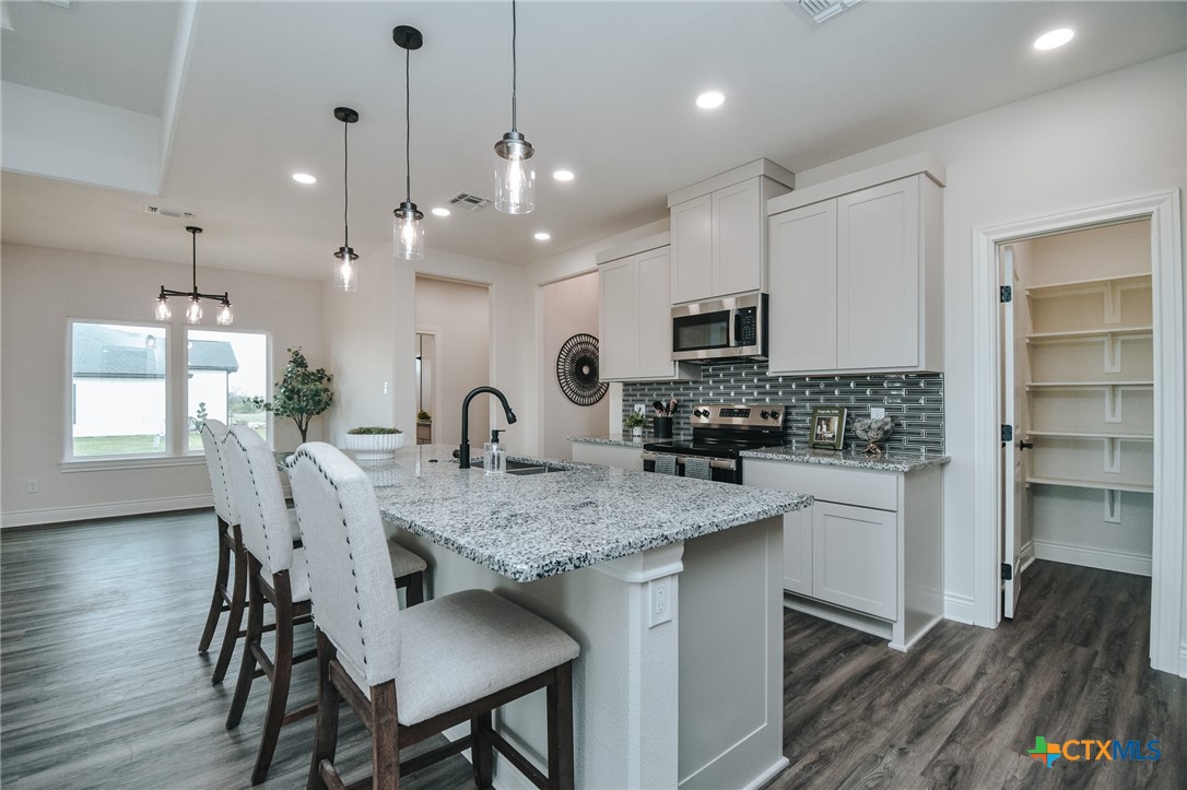 321 Whitetail Lane Victoria, TX 77905 - Photo 8 of 47 a kitchen with stainless steel appliances granite countertop a kitchen island a stove a table and chairs in it