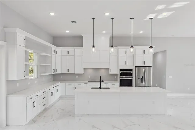 a large white kitchen with stainless steel appliances kitchen island granite countertop a granite counter tops and a sink