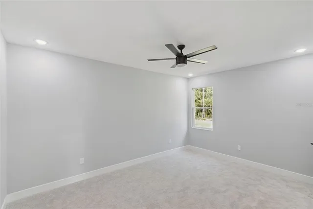 an empty room with a window and a ceiling fan